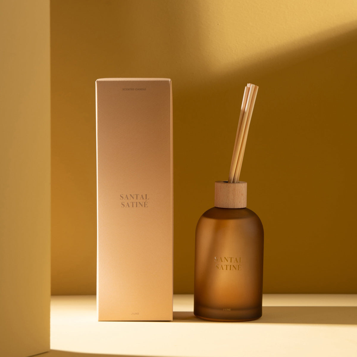 Geurstokjes Accords Essentiels Santal Satiné 250ml van J-Line met bijpassende doos in een sfeervolle gele setting