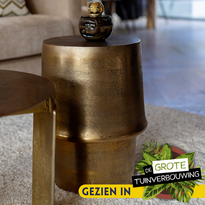 Bijzettafel Glamor Aluminium Goud van Starfurn in een woonkamer, naast een fauteuil met een kussen