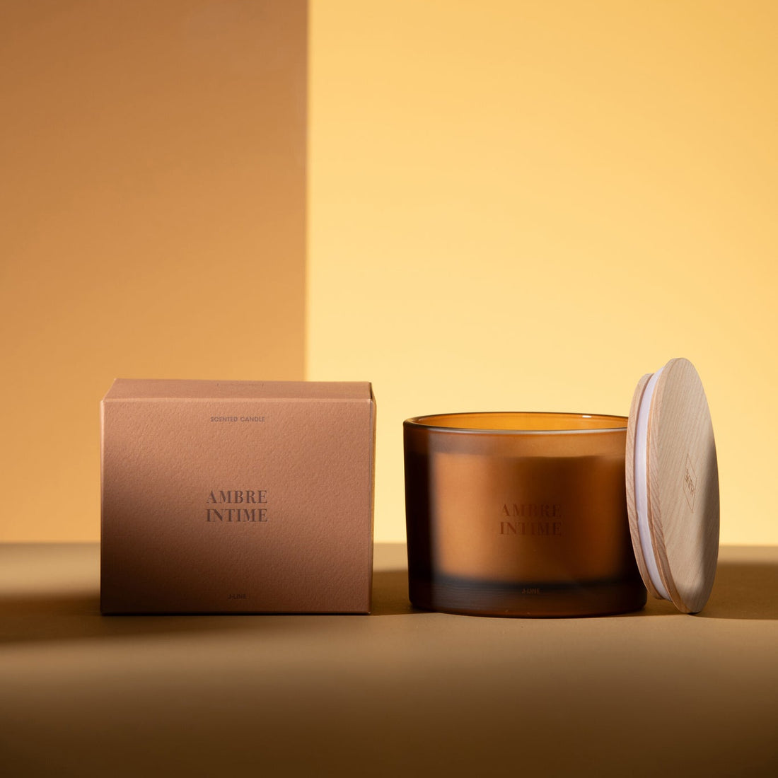 Geurkaars Accords Essentiels Ambre Intime 28 Uur van J-Line met bijpassende doos in een sfeervolle okerkleurige setting