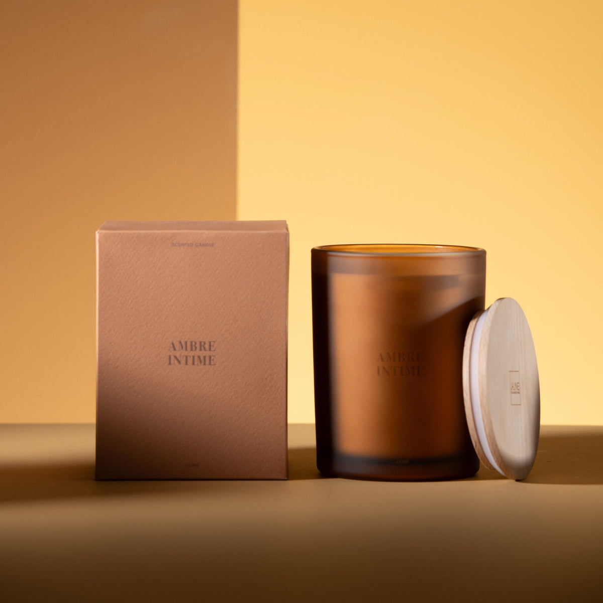 Geurkaars Accords Essentiels Ambre Intime 52 Uur van J-Line met bijpassende doos in een sfeervolle okerkleurige setting