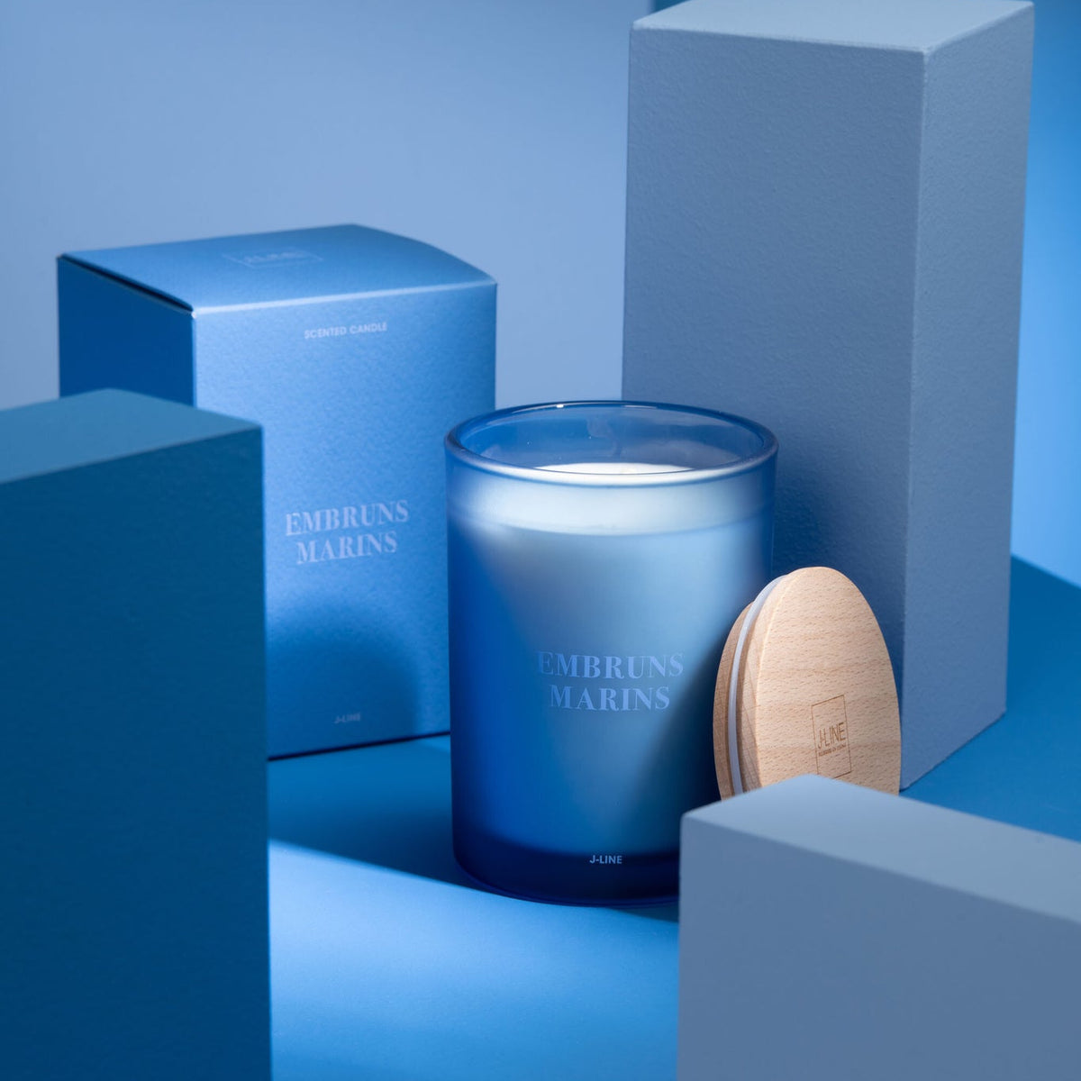 Geurkaars Accords Essentiels Embruns Marins 38 Uur van J-Line met bijpassende doos in een sfeervolle blauwe setting