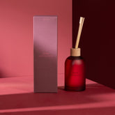 Geurstokjes Accords Essentiels Rose Séduisante 250ml van J-Line met bijpassende doos in een sfeervolle rode setting