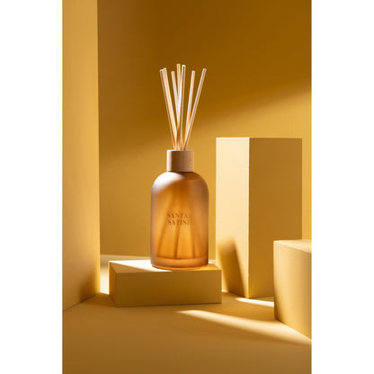 Geurstokjes Accords Essentiels Santal Satiné 250ml van J-Line op decoratieve blokken in een warme sfeerfoto