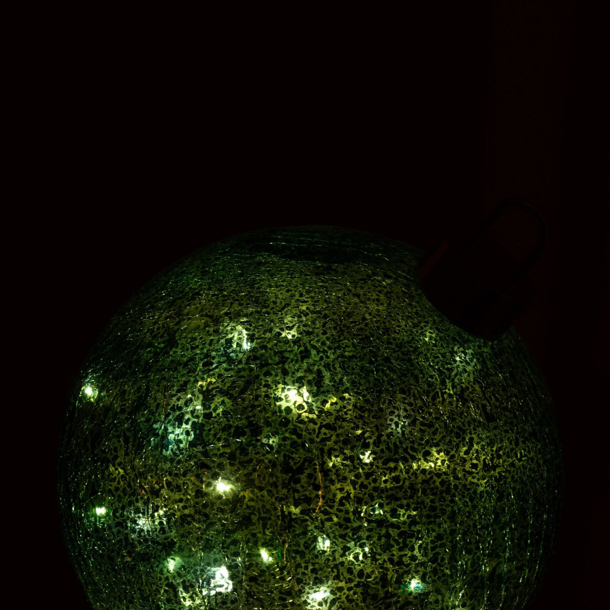 Grote turquoise kerstbal van J-Line die met ledverlichting warm gloeit in een donkere kamer
